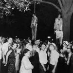 White people witnessing a lynching with lunch and a smile.