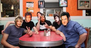 Photo of Moonlight Desires band members sitting at a red table