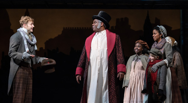 Photo of Gregory Maheu (Bob Cratchit), Craig Wallace (Ebenezer Scrooge), Ariel Russell (Martha Cratchit), Aiden Fuller (Tiny Tim) and Yesenia Iglesias (Mrs. Cratchit) in the Ford’s Theatre 2018 production of “A Christmas Carol” at Ford’s Theatre.