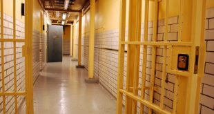 A prison corridor with open cell door and open prison gate