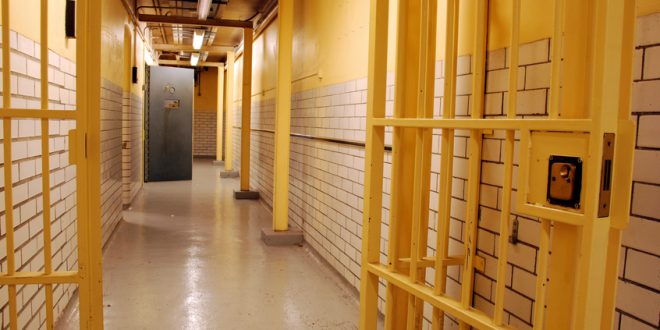 A prison corridor with open cell door and open prison gate