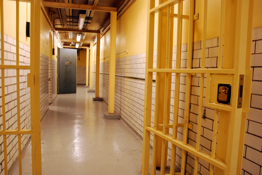 A prison corridor with open cell door and open prison gate
