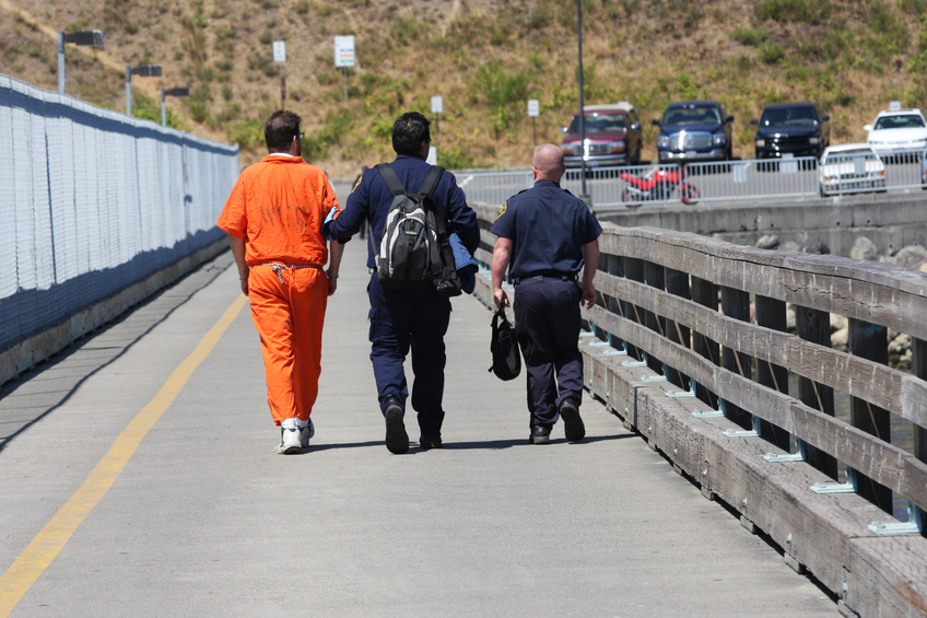 Correctional Officers escorting an offender in waist chains.
