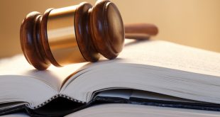Gavel Resting On Top Of Stack Of Open Law Books