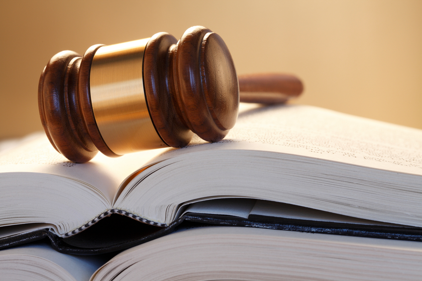 Gavel Resting On Top Of Stack Of Open Law Books
