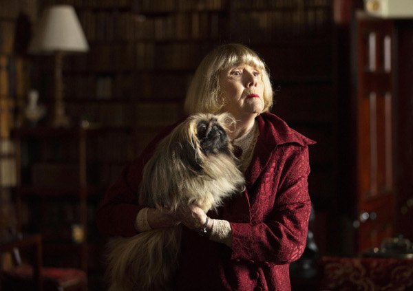 Photo of Dame Diana Rigg holding a small dog on the set of All Creatures Great and Small