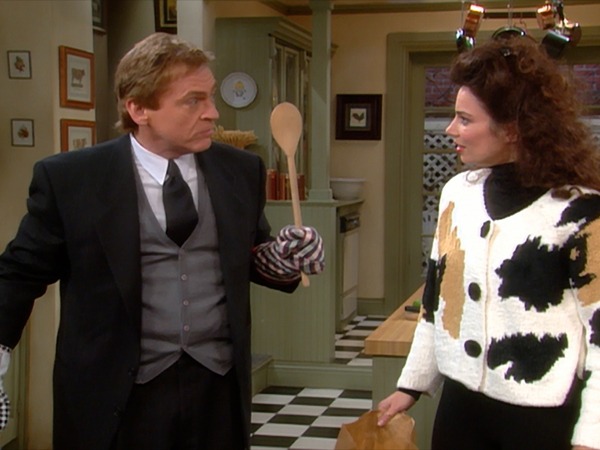 Image of Daniel Davis holding a spatula as Niles the Butler while standing by Fran Drescher as Fran Fine in the kitchen