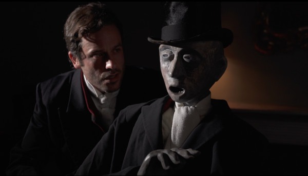 Photo of actor Dominic Gerrard with a puppet of Ebenezer Scrooge during a performance of 'A Christmas Carol'