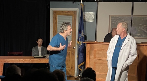 Production photo of a courtroom scene with Rachel Frost, Emanuele Secci, Robert Eigen, and Richard Clodfelter