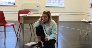 Photo of Gabrielle MacPherson crouching in a rehearsal of 'Outside'