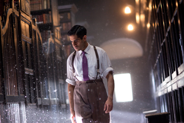 Photo of Sacha Dhawan as Garrett walking through the library