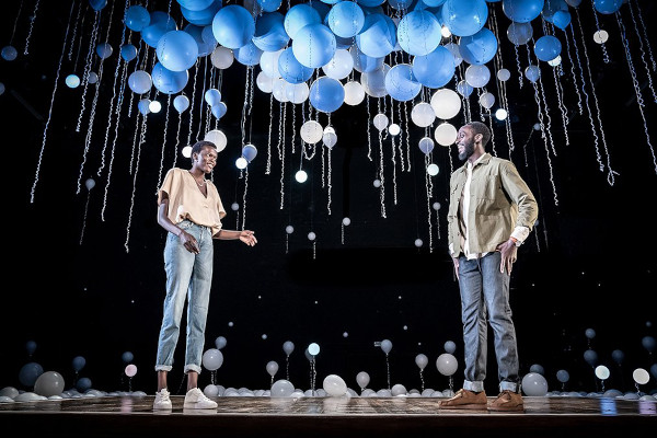 Photo of Sheila Atim and Ivanno Jeremiah standing onstage under balloons