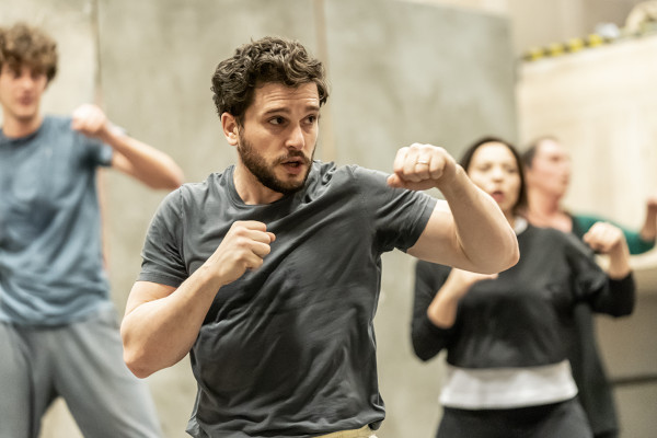 Cast of Henry V standing with fists raised during rehearsal