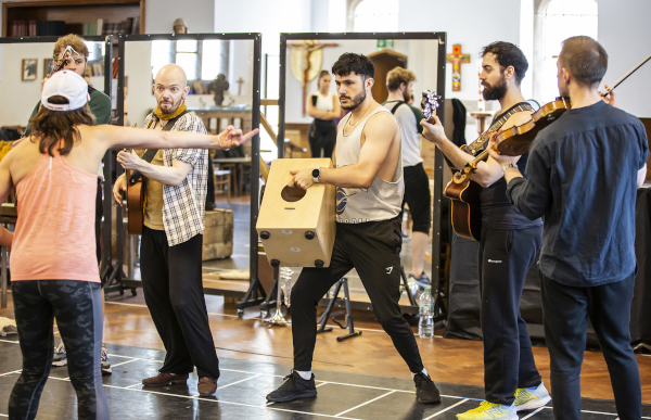 Photo of actors holding boxes and instruments in a rehearsal