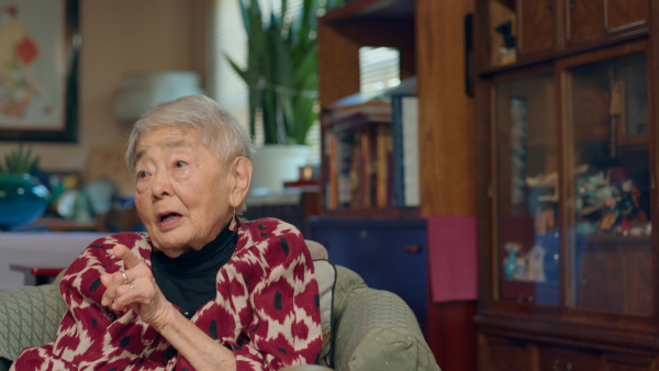 80 Years Later production still of Kiyoko Kasai Fujiu sitting in a chair and talking