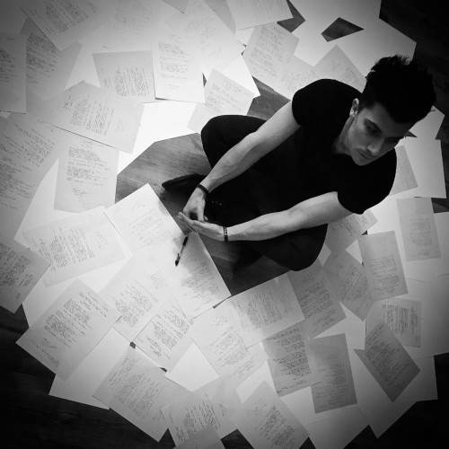 Ben Christo sitting on the floor, surrounded by pages of music