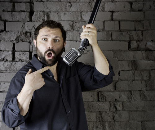 Photo of Brian Drummond holding a microphone