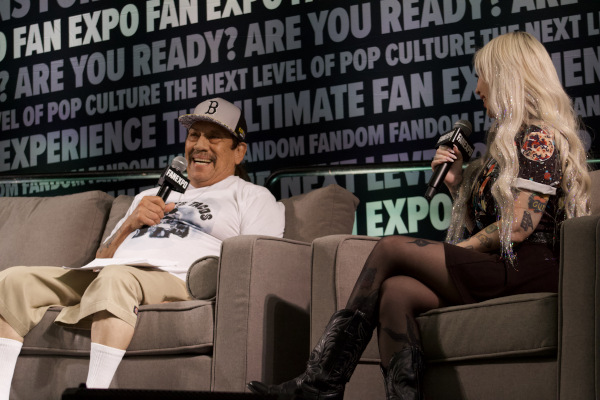 Photo of Danny Trejo holding a microphone and speaking with the moderator