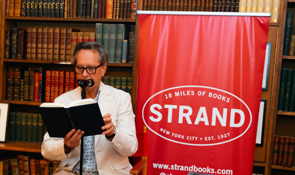 Photo of actor Richard E. Grant reading his memoir out loud