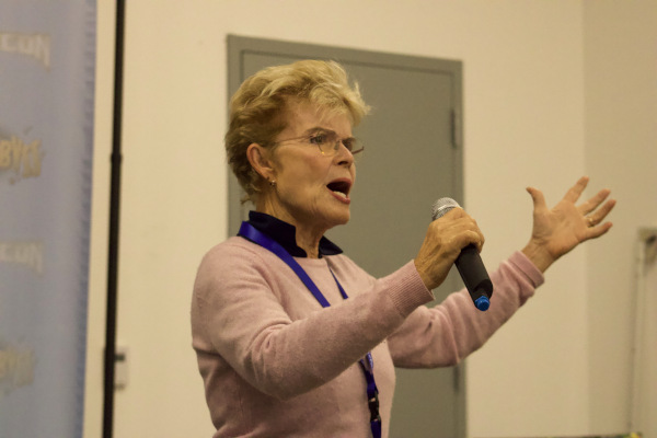 Photo of Sue Blu gesturing and holding a microphone at her panel