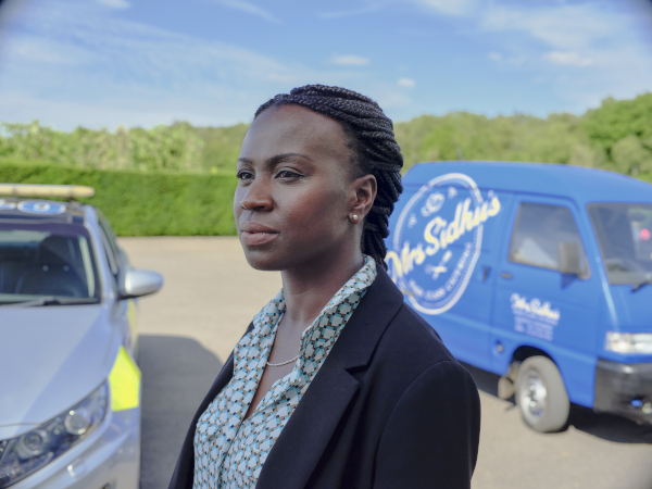 Photo of actor Naana Agyei Ampadu looking pensive outside near a blue catering van
