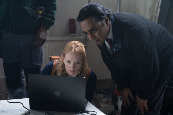 Photo of Carolina Main looking at a laptop as Sanjeev Bhaskar stoops to look at her laptop screen