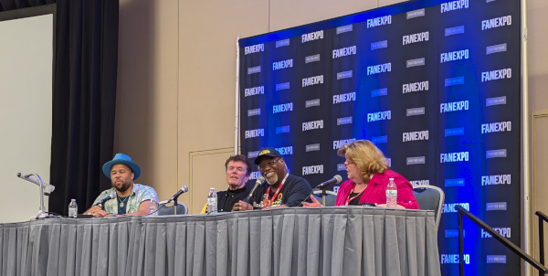 Photo of Victor Dandridge with X-Men '97 panelists Cal Dodd, Larry F. Houston, and Catherine Disher sitting at a table and speaking to the audience