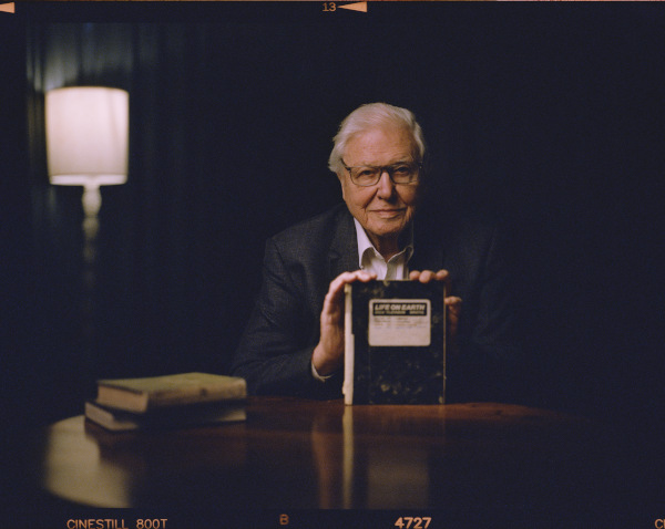 man sitting at a table and holding up a diary labelled Life on Earth